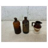 Two Amber Glass Bottles and Ceramic Pitcher