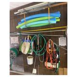 Assorted Garage Storage Lot including Hoses, Extension Cords, Pool Noodles, and Poles