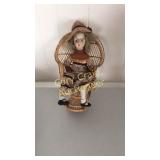 Porcelain doll with wicker chair