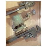 Two small pipe wrenches on a bench vice small