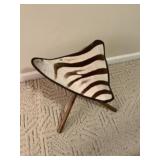3 legged stool with what appears to be zebra hide