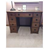 An antique style mahogany desk has nine drawers
