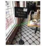 “Please wait to be seated” sign