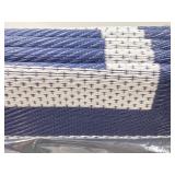 woven plastic outdoor rug featuring a navy blue an