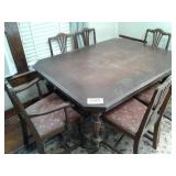 OLD TABLE ON CASTERS W 6 CHAIRS (1 IS A CAPTAINS
