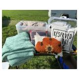 Two totes full of bedding, pillows and blankets .