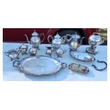 Several pieces of silver plate teapots serving