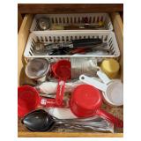 Drawer of measuring cups, can openers, misc