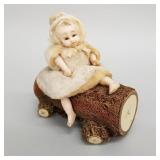 Antique wax doll on log candy container, glass