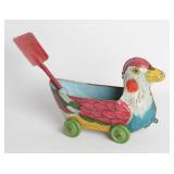 A DUCK FORM TIN LITHO DRAG-A-LONG WITH SHOVEL