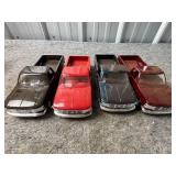 Four Plastic Model Pickup Trucks in Various Colors