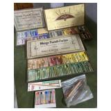 Collection of pastel chalks, oil pastels, and