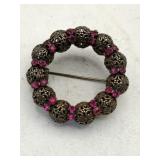 Circular filigree bead and pink rhinestone brooch