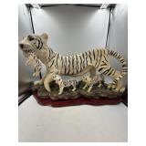 Large white tiger and cubs statue on wood.