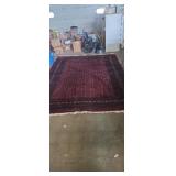 Large red Bokhara-style wool rug has some damage