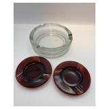 Two tangerine red ashtrays, one clear glass