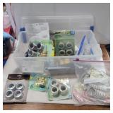 Curtain grommets and tools in container with lid