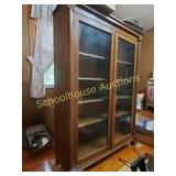 Wood cabinet with glass doors and shelves. About