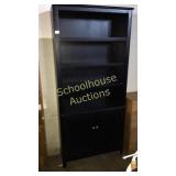 Large black bookshelf with cabinet.
Rough