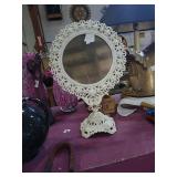 Tilting cast metal pedestal vanity mirror.