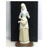 Porcelain Figurine of woman on wood stand. 11in H