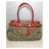 Coach purse with red straps and tassel.