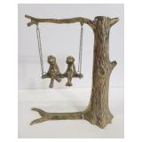 Brass frogs on a tree swing.