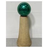 Green gazing ball on cement pedestal stand