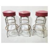 Three vintage red top stools with metal frames
