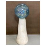 Blue glass gazing ball on cement stand
