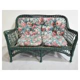 Vintage green wicker sofa with floral cushions