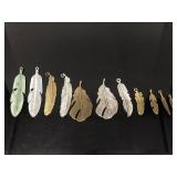 Eleven silver/gold toned feather pendants