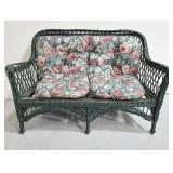Vintage green wicker sofa with floral cushions