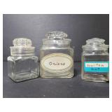 Three small glass canisters w/ lids
