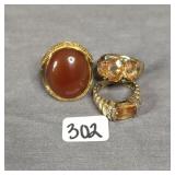 Various gold tone cocktail rings featuring orange