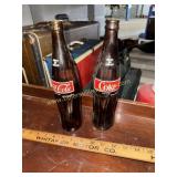 Two brown Coca Cola bottles