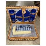 Wicker Picnic Basket with Blue Plates, Mugs, and Linens