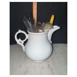 Porcelain pitcher with vintage spoons and other flatware