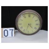 Round wall clock with Roman numeral face