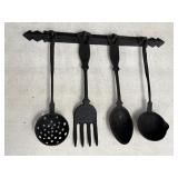 Rustic cast iron kitchen utensils on a wall hanger
