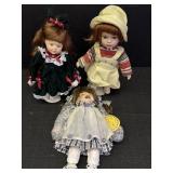 3 11in porcelain dolls, 1 not on stand is numbered