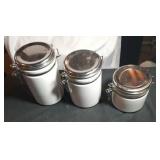 3 white canisters with bales