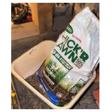 Plastic bucket and open bag of lawn seed