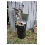 Trash can with garden tools including shovels,