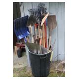 Trash can with garden tools including shovels,
