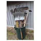 Trash can with garden tools including shovels,