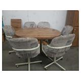 Oval table with 6 chairs on wheels and one leaf
