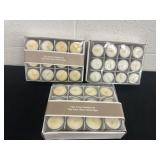3 boxes of votive candles in cups.
