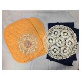 2 orange oval placemats; 2 doilies;