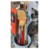 a bucket of gardening tools & brooms (by bobcat)